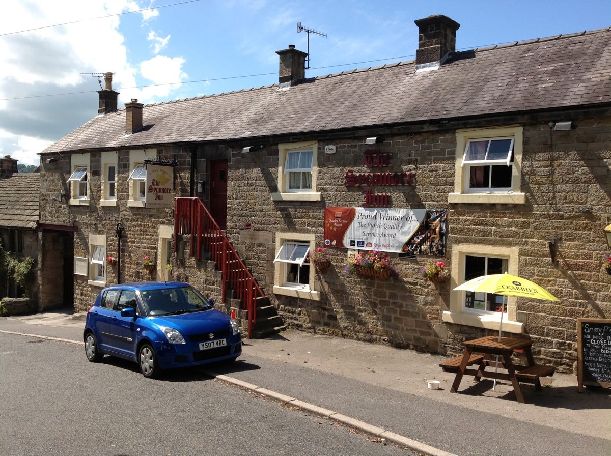 The stone-built inn with red outside steps and a picnic bench